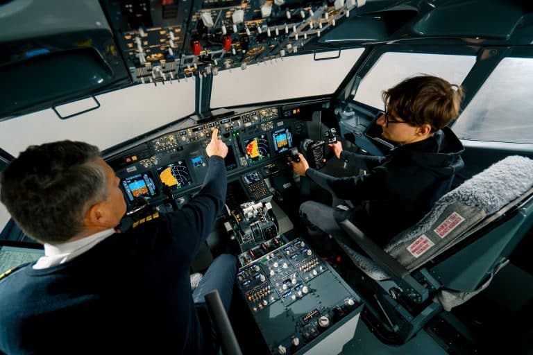 An experienced pilot instructs a young student before a training flight in the cockpit of an aero simulator
